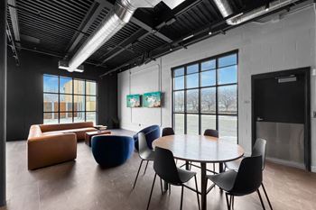 A room with a table, chairs and a painting on the wall.